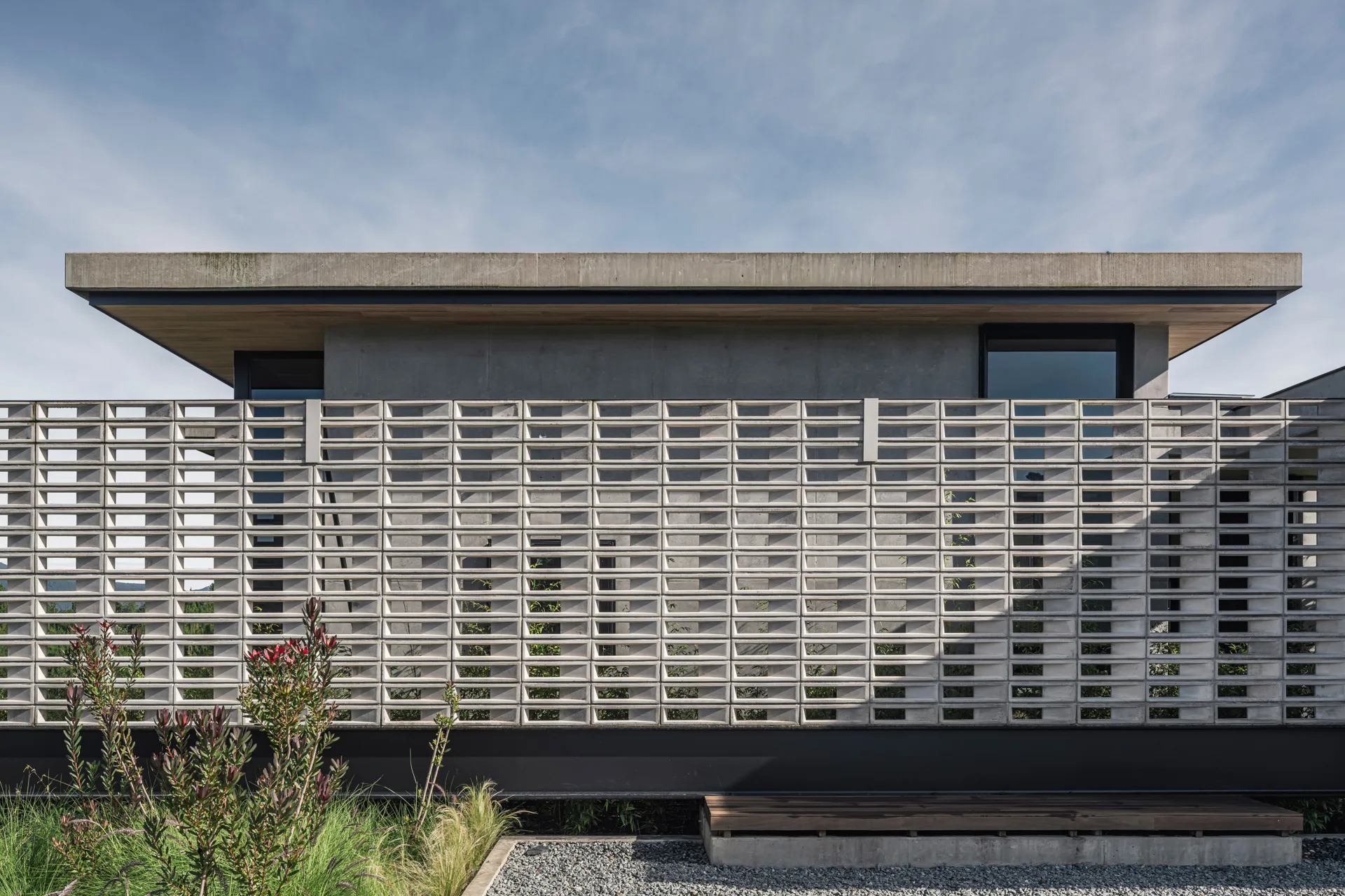 Fachada residencial en concreto a la vista pigmentado y madera de Casa Compostela en La Ceja por Llano Arquitectos.
